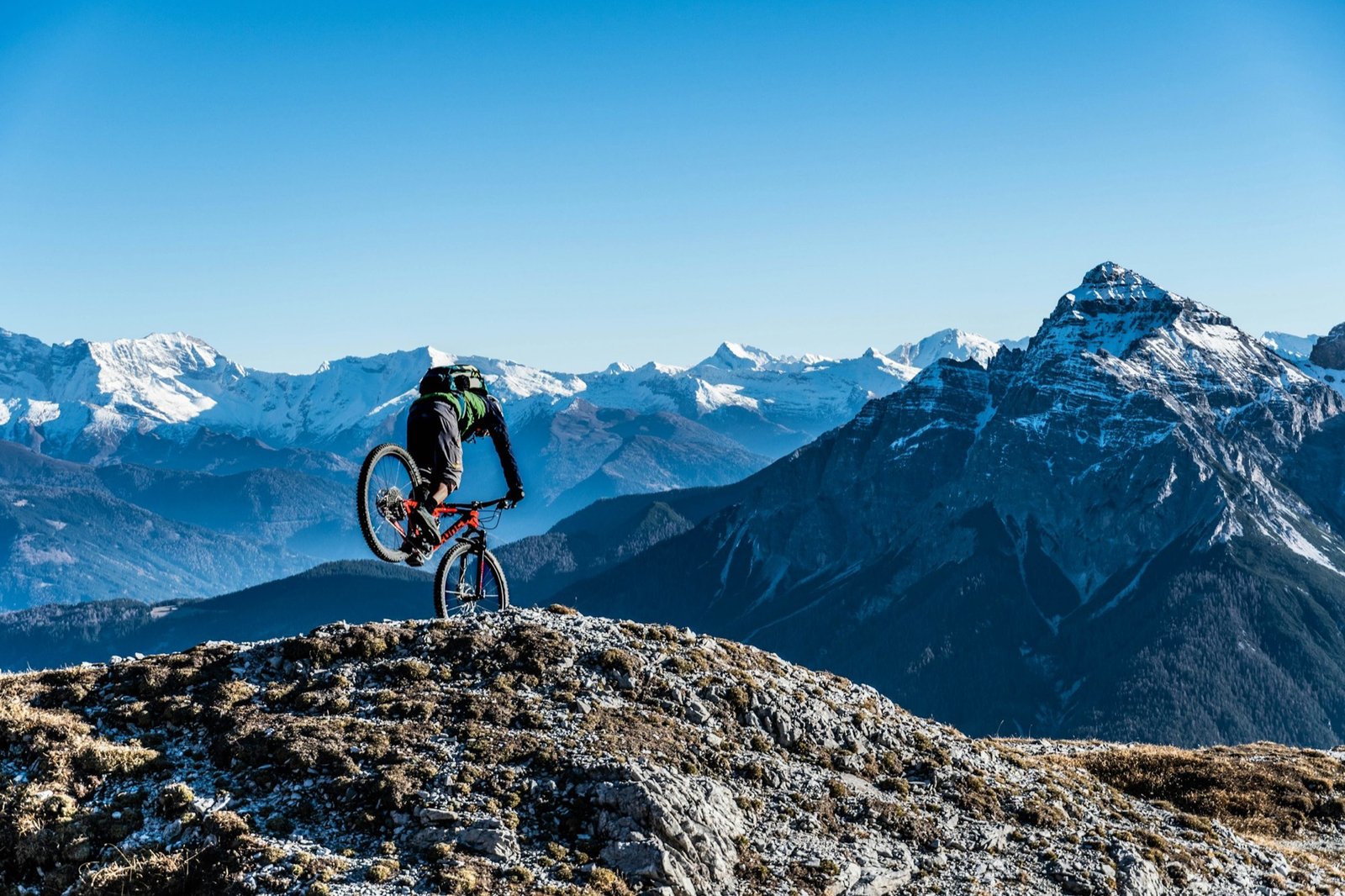 Mountainbiker auf einem Gipfel mit Alpenpanorama