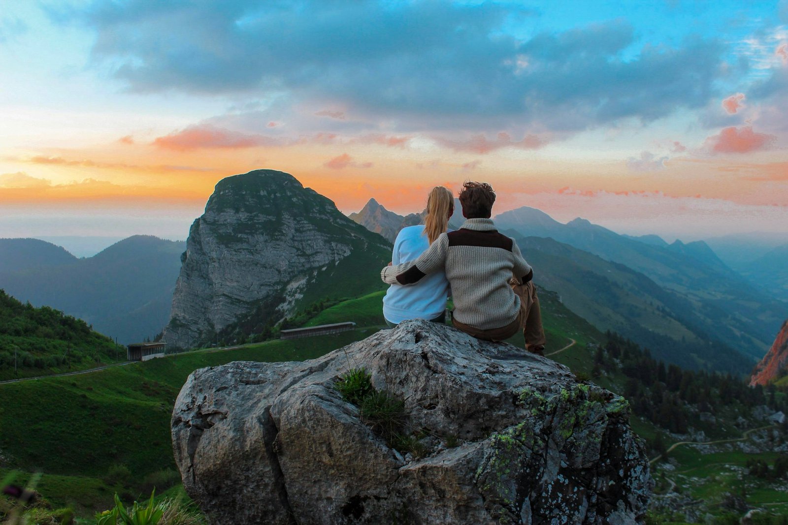 Paar rastet auf einem Felsen mit Blick auf die Berge